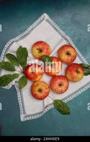 Äpfel auf einer weißen Serviette auf türkisfarbenem Hintergrund mit Platz für Text. Einfache Komposition Stillleben mit rotem Apfel. Stockfoto