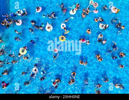 Peking, China. Juli 2024. Ein Foto der Drohne vom 14. Juli 2024 zeigt die Abkühlung in einem Wasserpark im Daoxian County, Stadt Yongzhou, in der Provinz Hunan in Zentralchina. Viele Touristenziele in ganz China haben in letzter Zeit einen Anstieg der Besucherzahlen erlebt, da das Land in die Hochsaison der Sommertourismussaison eintritt. Quelle: Jiang Keqing/Xinhua/Alamy Live News Stockfoto