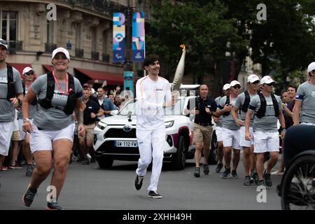 14. Juli 2024, Paris, Frankreich. Ein Fackelträger führt die olympische Fackel durch den Place de la Bastille, während sie durch Paris fährt. Quelle: Jay Kogler/Alamy Live News Stockfoto