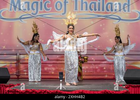 Damen in traditioneller Kleidung führen eine Tanzroutine auf einer Bühne beim Thai Food and Craft Festival in Southsea auf. Juli 2024 Stockfoto