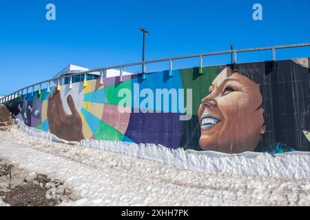 Inuit Frau umarmen Wandbild unter dem Thema „Kommen Sie zusammen“ im Qikiqtani General Hospital in Iqaluit, Nunavut, Kanada Stockfoto