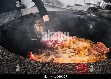 In der Küche eines Restaurants in Usbekistan in Taschkent kocht der männliche Koch Lammfleisch im Kessel für das traditionelle asiatische usbekische Pilaw Stockfoto