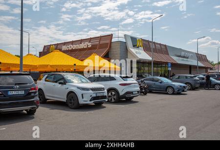 Lisniki, Kiew, Ukraine - 18. Mai 2024: Autos parken vor McDonald's Fast-Food-Restaurant. Es ist eine multinationale amerikanische Fast-Food-Kette, gefunden Stockfoto