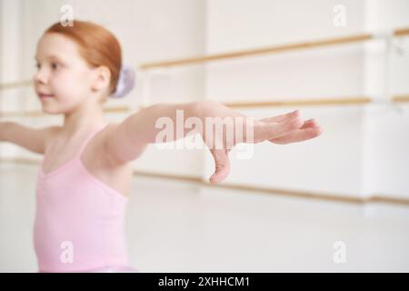 Ein junges Ballettmädchen beim Studiounterricht. Trainingsleistung. Stretching-Übungshaltung. Ballerina-Praxis-Balance-Technik. Klassische Eleganz Fitness. Tanzkostüm. Nahaufnahme. Pinkfarbenes Kleid, Rock Stockfoto