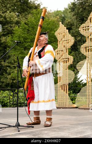 Vilnius, Litauen - 2. Juli 2024: Mann in traditioneller Tracht, der slowakische Fujara-Volksinstrumente auf der Bühne spielt Stockfoto
