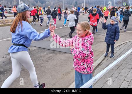 7. April 2024: Moskau, Russland: Traditionelles 5-km-Rennen im Luschniki-Stadion. Das kleine Zuschauermädchen begrüßt die junge Amateurläuferin Stockfoto