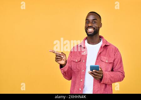 Glücklicher afrikanischer Mann mit Handy in Händen isoliert auf gelbem Weg. Stockfoto