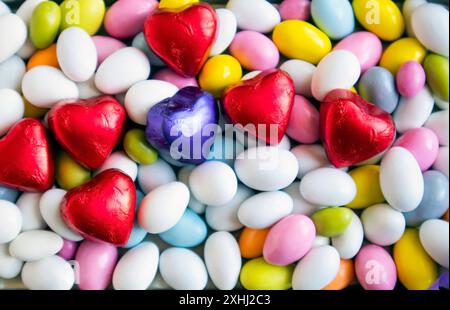 Bunte Mandelbonbons wurden mit herzförmigen gewickelten Pralinen gestaltet. Blick von oben Stockfoto