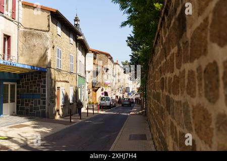 Langeac, Frankreich - 28. Mai 2023: Eine enge, kopfsteingepflasterte Straße in Langeac, Frankreich, gesäumt von alten Steinhäusern und lebhaftem Grün. Stockfoto