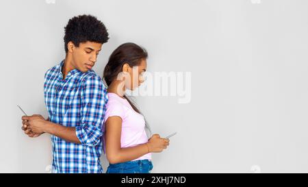 Teenager-Paar, Das Smartphones Gegen Die Weiße Wand Benutzt Stockfoto