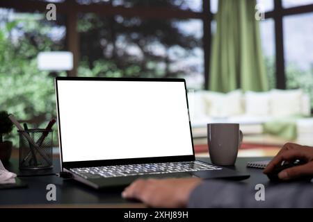 Der Milliardär-Regisseur entspannt sich vor dem weißen Display auf Laptop, luxuriöse Berghütte. In einem erfolgreichen Unternehmen arbeitet der General Manager mit einem leeren Modellbildschirm auf dem pc. Stockfoto