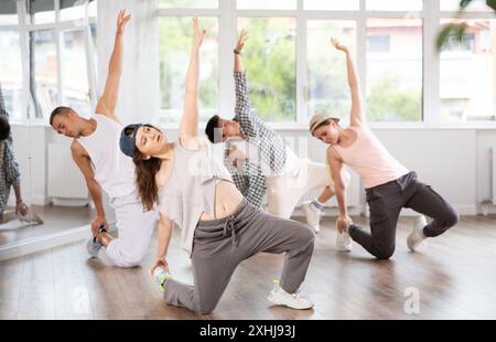 Mädchen und ihre Schüler führen Hip-Hop-Tanz auf einem gebogenen Bein auf, Bewegung in horizontaler Ebene in Bodennähe Stockfoto