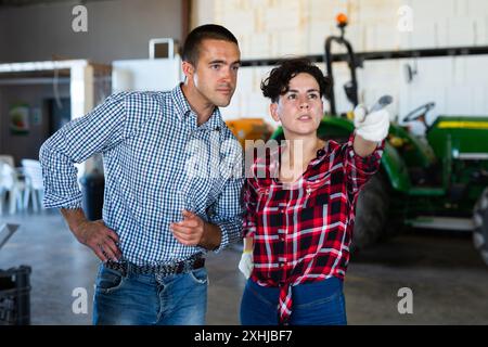 Zwei Gärtner arbeiten im Gewächshaus. Eine geschickte Frau zeigt und sagt dem Mann etwas Stockfoto