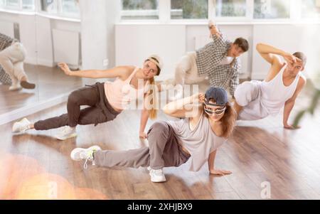 Mädchen und ihre Schüler führen Hip-Hop-Tanz auf einem gebogenen Bein auf, Bewegung in horizontaler Ebene in Bodennähe Stockfoto