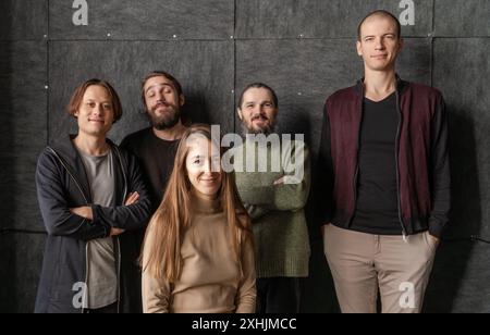 Gruppenporträt von fünf Freunden, die zusammen posieren, lächeln vor dunklem Hintergrund, Kameradschaft und Zweisamkeit. Stockfoto