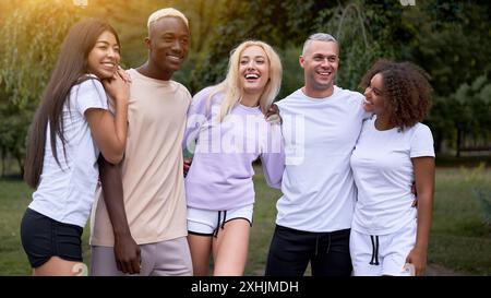 Freunde im Teenageralter mit mehreren ethnischen Gruppen. Afroamerikanische asiatisch-kaukasische Studenten verbringen Zeit miteinander multirassische Freundschaft. Glückliche lächelnde Menschen in Sportbekleidung treffen sich im Park. Stockfoto