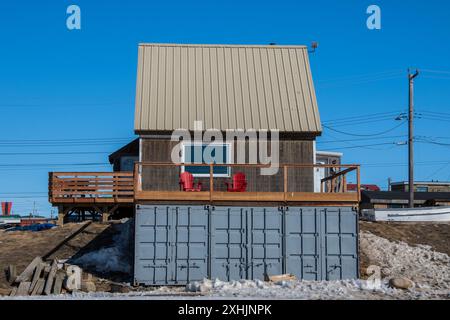 Rote Adirondack-Stühle auf einem Balkon über einem Versandcontainer am Iglulik Drive in Iqaluit, Nunavut, Kanada Stockfoto