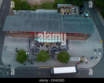 Blick aus der Vogelperspektive auf eine geschäftige Bar im Stadtzentrum in der Abenddämmerung, bei der Gäste Getränke und Speisen genießen Stockfoto