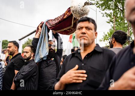 Srinagar, Indien. Juli 2024. Ein kaschmirischer schiitischer Mann geht mit einer Alam (Flagge) während einer Muharram-Prozession am siebten Tag des Muharram. Muharram ist der erste Monat des islamischen Kalenders. Es ist einer der heiligsten Monate im islamischen Kalender. Schiitische Muslime gedenken Muharram als einen Monat der Trauer zum Gedenken an das Martyrium des islamischen Propheten Muhammads Enkel Imam Hussain, der in der Schlacht von Karbala 680 n. Chr. auf Ashura (10. Tag Muharram) zum Märtyrertod verurteilt wurde. Credit: SOPA Images Limited/Alamy Live News Stockfoto