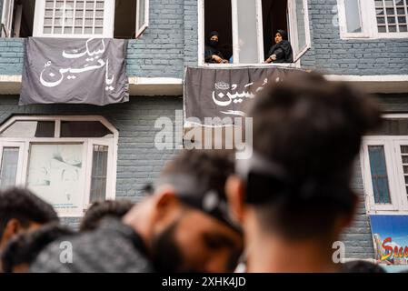 Srinagar, Indien. Juli 2024. Kaschmiri schiitische Frauen beobachten am siebten Tag Muharrams eine Trauerprozession von den Fenstern aus. Muharram ist der erste Monat des islamischen Kalenders. Es ist einer der heiligsten Monate im islamischen Kalender. Schiitische Muslime gedenken Muharram als einen Monat der Trauer zum Gedenken an das Martyrium des islamischen Propheten Muhammads Enkel Imam Hussain, der in der Schlacht von Karbala 680 n. Chr. auf Ashura (10. Tag Muharram) zum Märtyrertod verurteilt wurde. Credit: SOPA Images Limited/Alamy Live News Stockfoto