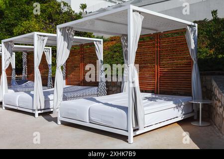 Strandliegen mit Vorhängen sind in einer Reihe angeordnet. Resort Himmelbett zum Entspannen im Freien Stockfoto