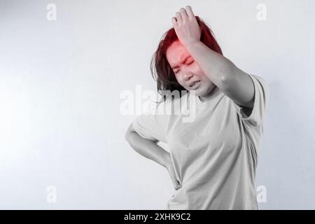 Nahaufnahme junger Frauen, die Schläfe mit Fingern berühren, als ob sie an schwerer Migräne leiden, sich krank fühlen, isoliert auf grauem Hintergrund Stockfoto