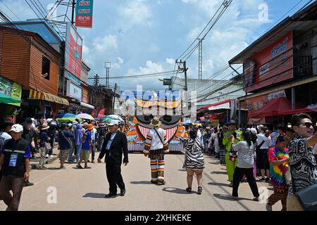 Ein farbenfroher Wagen, der mit einer „Geistermaske“ verziert ist, geht auf dem Weg entlang der Prozession beim Phi Ta Khon Festival, Dan Sai, Loei, Thailand Stockfoto