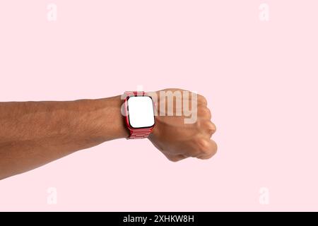 Männliche Hand, die eine rote Metall-Smartwatch trägt, isoliert auf rosafarbenem Hintergrund Stockfoto