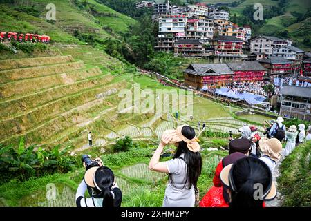 (240715) -- LONGSHENG, 15. Juli 2024 (Xinhua) -- Touristen werden während eines traditionellen Festivals im Dorf Dazhai im County Longsheng, südchinesischer Autonomen Region Guangxi Zhuang, 11. Juli 2024, fotografiert. Hinter den malerischen Longji Rice Terrassen liegt das Dorf Dazhai, flankiert von üppigem Grün, majestätischen Bergen und einer vielfältigen Auswahl an Gastfamilien. Das Dorf wurde von der Welttourismusorganisation (UNWTO) für seine atemberaubende landwirtschaftlich geprägte Aussicht zu den besten Tourismusdörfern des Jahres 2022 ernannt und ist stolz auf seine robusten Gastfamilien, die jährlich mehr als 500.000 Yuan (ca. Stockfoto