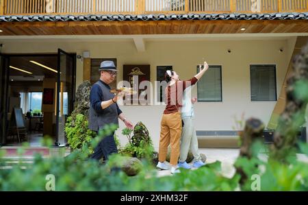 (240715) -- LONGSHENG, 15. Juli 2024 (Xinhua) -- Li bin (1. L) serviert Touristen Tee in der Gastfamilie, die er im Dorf Dazhai des Bezirks Longsheng, südchinesischer Autonomer Region Guangxi Zhuang betreibt, 26. Juni 2024. Hinter den malerischen Longji Rice Terrassen liegt das Dorf Dazhai, flankiert von üppigem Grün, majestätischen Bergen und einer vielfältigen Auswahl an Gastfamilien. Das Dorf wurde von der Welttourismusorganisation (UNWTO) für seine atemberaubende Aussicht auf die Landwirtschaft zu den besten Tourismusdörfern des Jahres 2022 ernannt und ist stolz auf seine robusten Gastfamilien, die jährlich mehr als 500 einbrachten Stockfoto