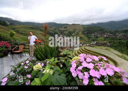 (240715) -- LONGSHENG, 15. Juli 2024 (Xinhua) -- Yu Qiongtong hat einen Geschäftsbesuch in der Gastfamilie, die er im Dorf Dazhai im County Longsheng, südchinesischer Autonomen Region Guangxi Zhuang, am 27. Juni 2024 betreibt. Hinter den malerischen Longji Rice Terrassen liegt das Dorf Dazhai, flankiert von üppigem Grün, majestätischen Bergen und einer vielfältigen Auswahl an Gastfamilien. Das Dorf wurde von der Welttourismusorganisation (UNWTO) für seine atemberaubende landwirtschaftlich geprägte Aussicht zu den besten Tourismusdörfern des Jahres 2022 ernannt und ist stolz auf seine robusten Gastfamilien, die jährlich mehr als 500.000 Yuan einbrachten Stockfoto