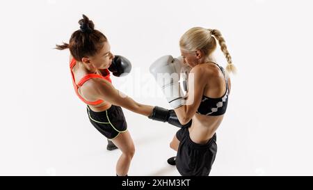 Zwei Frauen, die sich in einem intensiven Boxkampf befinden, zeigen Stärke und Beweglichkeit, konkurrieren mit Fokus und Intensität isoliert auf weißem Hintergrund Stockfoto