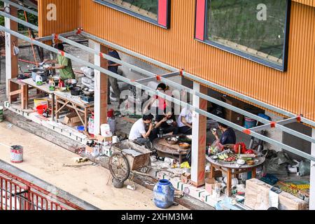 (240715) -- LONGSHENG, 15. Juli 2024 (Xinhua) -- Arbeiter essen am 26. Juni 2024 auf der Baustelle einer Gastfamilie im Dorf Dazhai im Bezirk Longsheng, südchinesischer Autonomen Region Guangxi Zhuang. Hinter den malerischen Longji Rice Terrassen liegt das Dorf Dazhai, flankiert von üppigem Grün, majestätischen Bergen und einer vielfältigen Auswahl an Gastfamilien. Dieses Dorf wurde von der Welttourismusorganisation (UNWTO) für seine atemberaubende landwirtschaftlich geprägte Aussicht zu den besten Tourismusdörfern des Jahres 2022 ernannt und ist stolz auf seine robusten Gastfamilien, die jährlich mehr als 500.000 Yuan ( Stockfoto