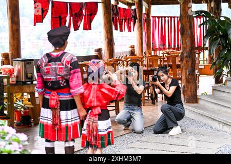 (240715) -- LONGSHENG, 15. Juli 2024 (Xinhua) -- Mitarbeiter machen Fotos für Touristen in einer Gastfamilie im Dorf Dazhai im Bezirk Longsheng, südchinesischer Autonomen Region Guangxi Zhuang, 11. Juli 2024. Hinter den malerischen Longji Rice Terrassen liegt das Dorf Dazhai, flankiert von üppigem Grün, majestätischen Bergen und einer vielfältigen Auswahl an Gastfamilien. Das Dorf wurde von der Welttourismusorganisation (UNWTO) für seine atemberaubende landwirtschaftlich geprägte Aussicht zu den besten Tourismusdörfern des Jahres 2022 ernannt und ist stolz auf seine robusten Gastfamilien, die jährlich mehr als 500.000 Yuan (ca. Stockfoto