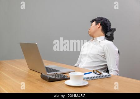 Ein Mann mit Narkolepsie schläft auf dem Schreibtisch ein. Narkolepsie ist eine Schlafstörung, die Menschen tagsüber sehr schläfrig macht. Stockfoto