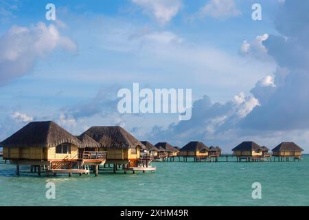 Französisch-Polynesien, Insel Taha'a, Bungalows auf Stelzen, die auf der Lagune des Taha'a Pearl Resort Hotels vor einem blauen und bewölkten Himmel liegen Stockfoto