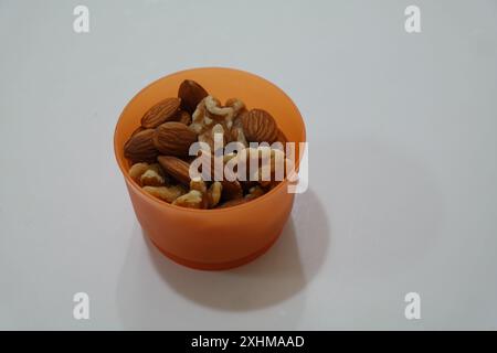 Mandel in orangefarbener Schüssel auf weißem Hintergrund Stockfoto