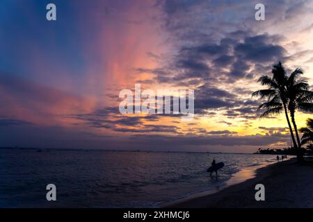 Surfer bei Sonnenuntergang an einem Strand auf Hawaii Stockfoto