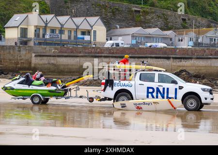 Ein RNLI-Rettungsschwimmer sitzt auf einem Rettungswagen, der am Towan Beach in Newquay in Cornwall in Großbritannien geparkt ist. Stockfoto