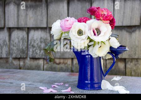 Blumenstrauß in einer blauen Kanne auf einem Metalltisch Stockfoto