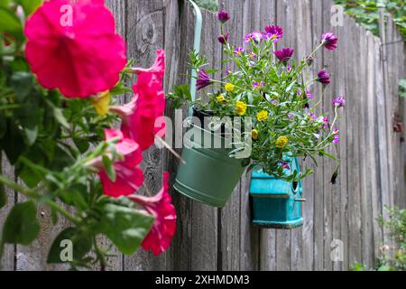 Bunte Blumen in Töpfen, die an einem Holzzaun hängen Stockfoto