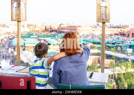 Junge mit Mutter, der auf die Märkte des Jemaa el Fna-Platzes in Marrakesch blickt Stockfoto