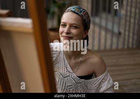 Frau Künstlerin malt auf Leinwand, Ölfarben. Staffelei auf Terrasse, Sommer. Stockfoto