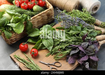 Verschiedene aromatische Kräuter, Gemüse und Scheren auf grauem Tisch, Nahaufnahme Stockfoto