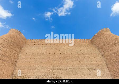 Die Mauer der Arche Buchara liegt an einem sonnigen Sommertag unter blauem bewölktem Himmel. Dies ist eine massive Festung in Usbekistan, die ursprünglich gebaut und gelegentlich gebaut wurde Stockfoto