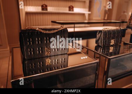 Luxuriöse schwarze Textil-Handtasche mit goldener Kette an einem Spiegelständer in einer berühmten Burberry Boutique. Burberry ist eine britische Luxusmarke. Fashio Stockfoto