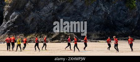 Ein Panoramablick einer Gruppe männlicher Urlauber, die Spiele spielen, um sich vor einer Surfstunde im Newquay Activity Centre auf GT Great Western B aufzuwärmen Stockfoto