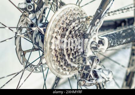 Vergrößertes Fahrradrad an der Autowaschanlage. Speichen, Kette. Fahrrad mit Schaum waschen. Wartung Stockfoto