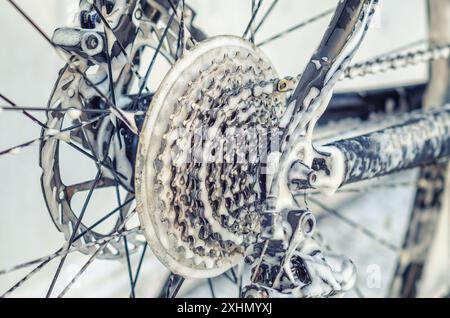 Vergrößertes Fahrradrad an der Autowaschanlage. Speichen, Kette. Fahrrad mit Schaum waschen. Wartung Stockfoto