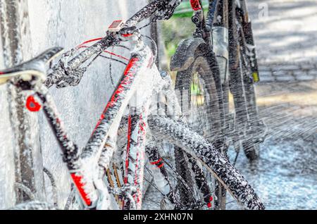 Fahrrad an der Autowaschanlage. Waschen Sie das Fahrrad mit einem Strahl aus weißem Schaum. Self-Service. Wartung Stockfoto